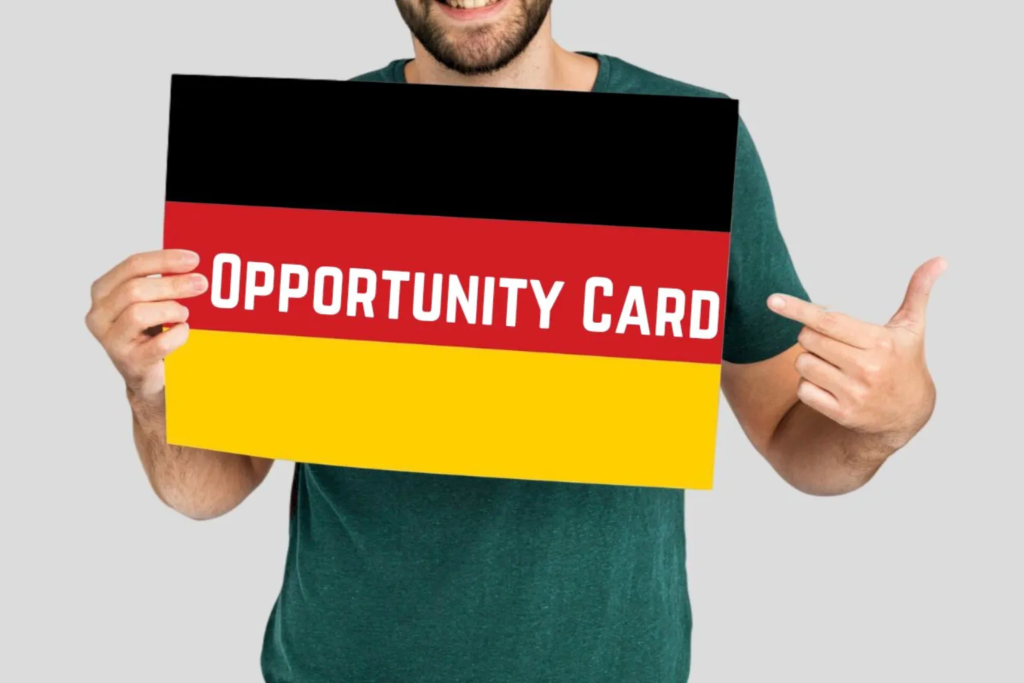 Smiling man holding Germany flag poster with the words "Opportunity Card" representing Germany’s Chancenkarte visa for skilled workers